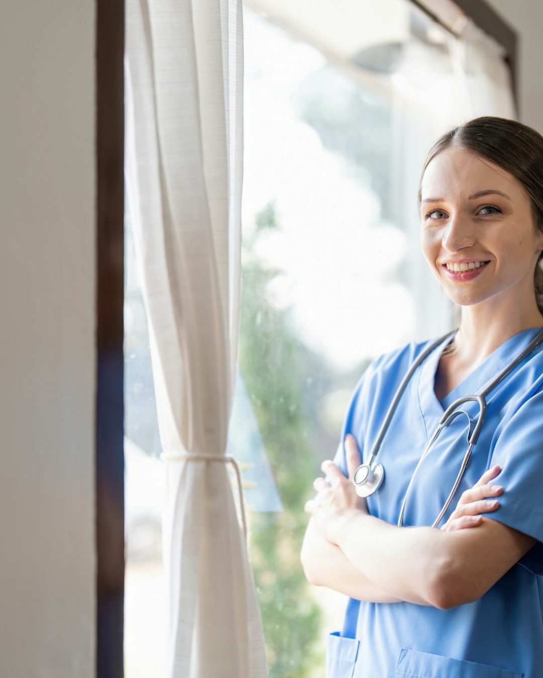 Portrait of a friendly female doctor or nurse wearing blue scrubs uniform and stethoscope, with